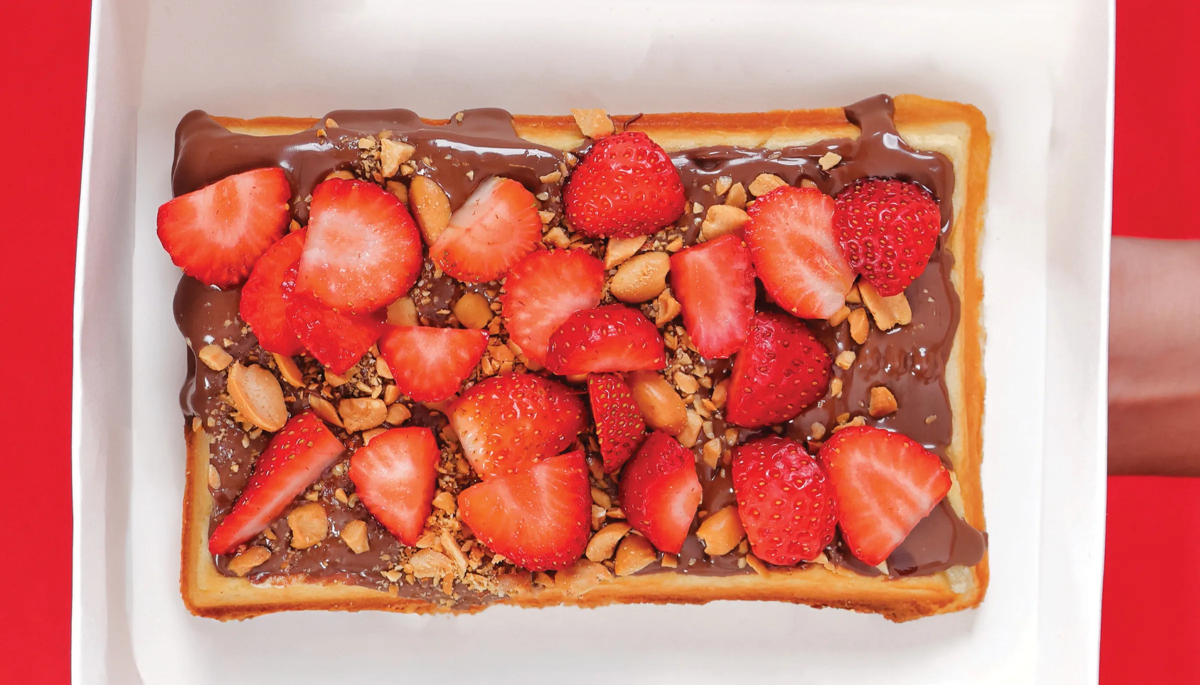 Chocolate waffle topped with strawberries and nuts